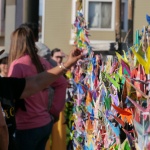 Women gather at a display of folder paper cranes
