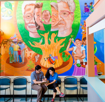 Doctor and patient in front of mural at a community health center